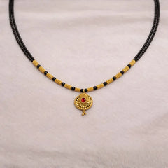 Black beaded Mangalsutra with gold accents and a red gemstone pendant o
