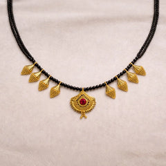 Black beaded necklace with gold pendants on a beige background