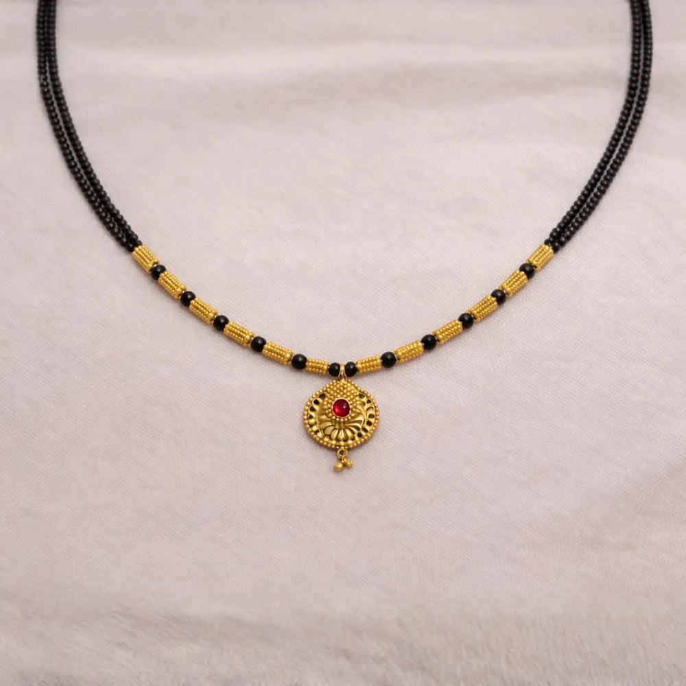 Black beaded Mangalsutra with gold accents and a red gemstone pendant o