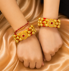 Two hands wearing gold and red pauji
