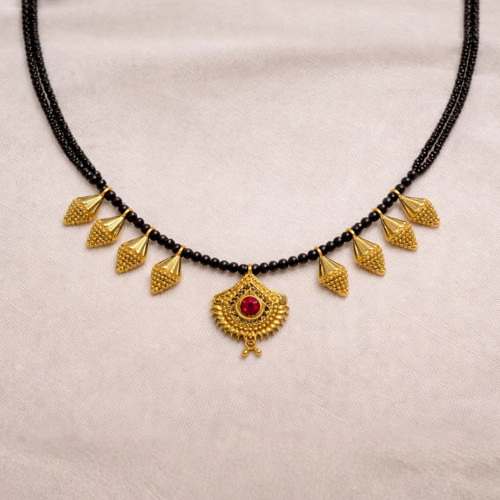 Black beaded necklace with gold pendants on a beige background