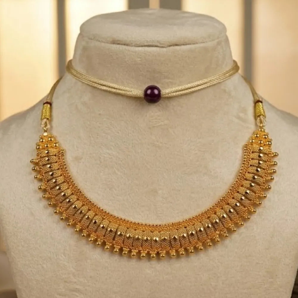Gold necklace with a purple bead on a mannequin bust.