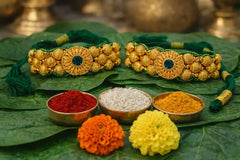 Gold jewelry on green leaves with colorful powders and flowers